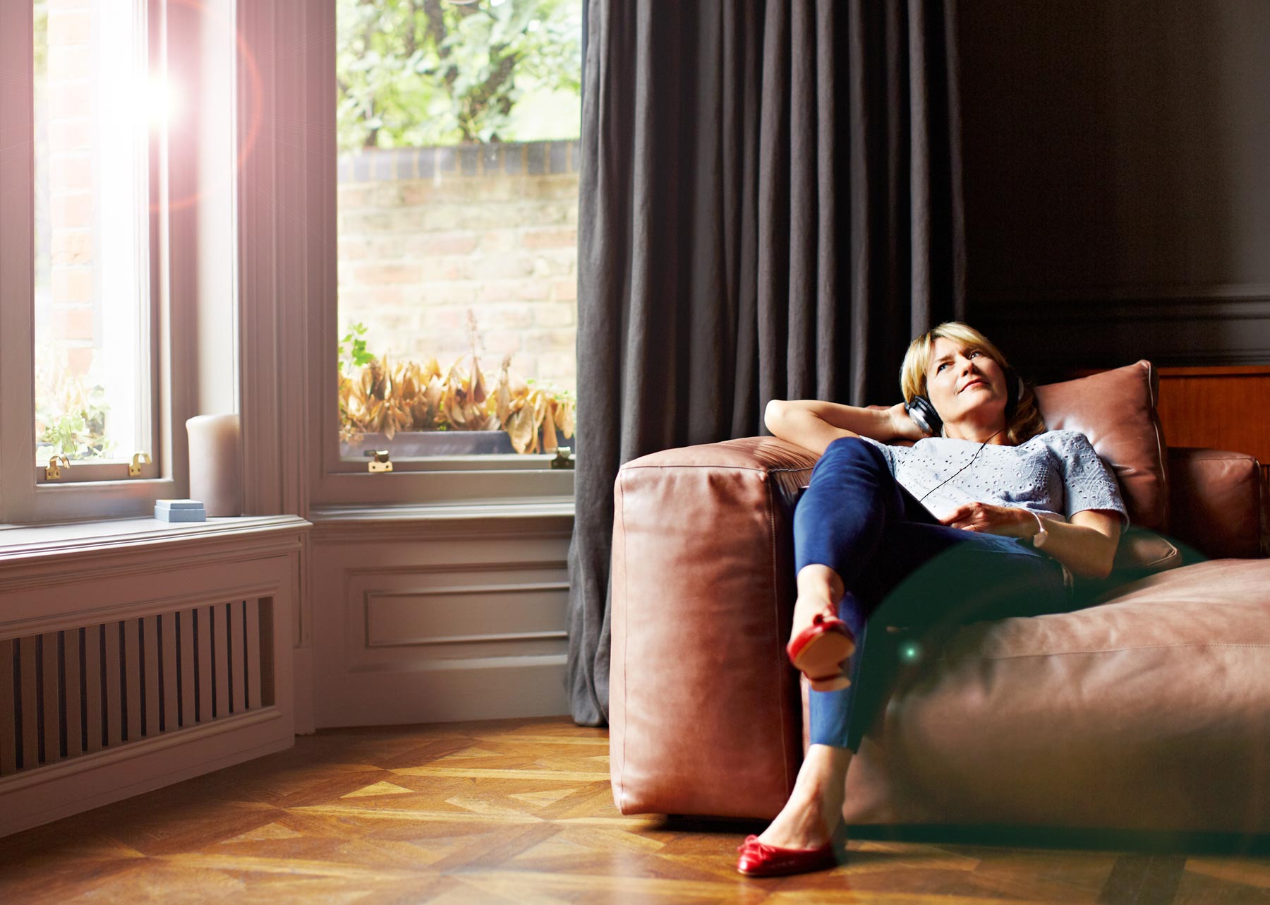Woman lounging on comfy sofa listening to music